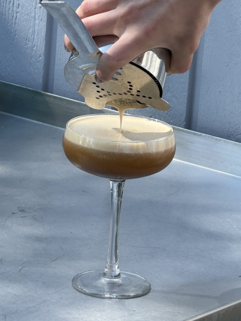 Espresso Martini sies ned i coupeglas på stålbord